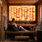 Woman Relaxing on Wooden Bench in Sauna with Backlit Himalayan Salt Brick Feature Wall